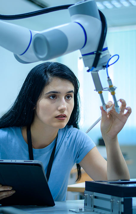 Eine Entwicklungsingenieurin mit Tablet arbeitet konzentriert an einem Roboterarm in einem modernen Labor.