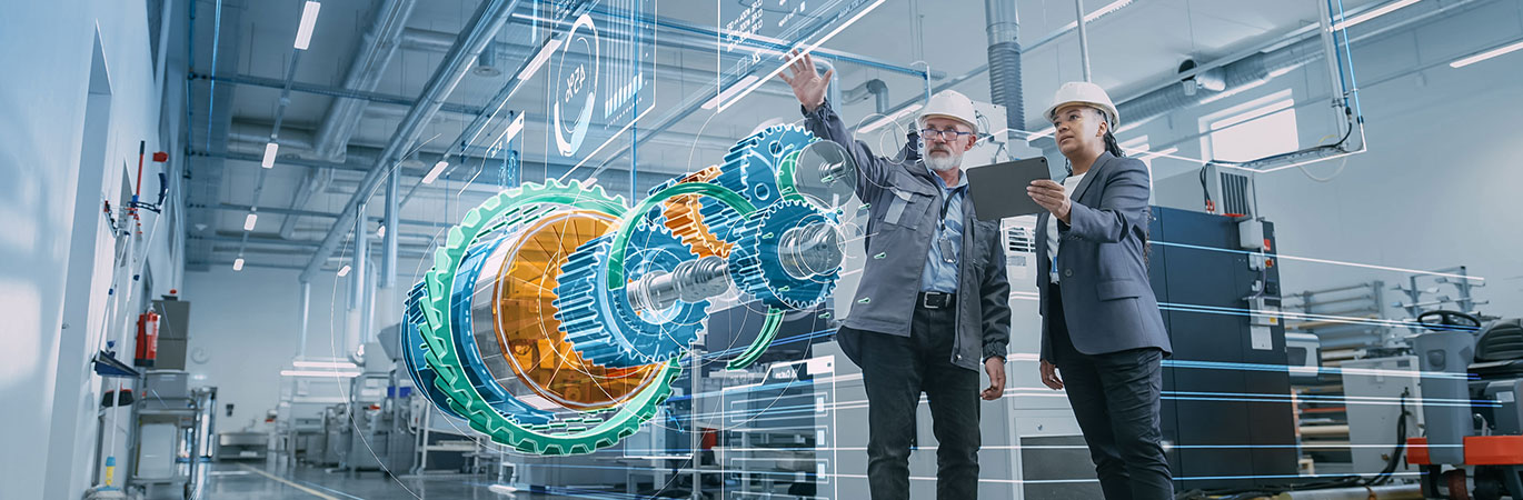 Zwei Ingenieure mit Schutzhelmen betrachten ein holografisches 3D-Modell eines Turbinenbauteils in einer modernen Fertigungshalle.