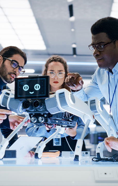 Eine Gruppe von Ingenieuren und Entwicklerinnen arbeitet gemeinsam an einem vierbeinigen Roboter mit Display im Forschungslabor.